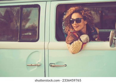 Retro classic travel vehicle and people concept. One Beautiful adult woman inside a blue van. Transport vehicle and freedom. Alternative lifestyle lady sith curly hair. Cheerful female traveler smile - Powered by Shutterstock