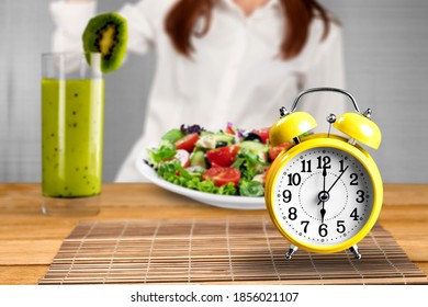 Retro clock in which woman make Intermittent fasting with a Healthy food of salad. - Shutterstock ID 1856021107