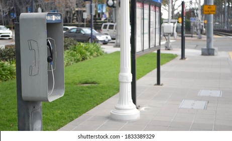 Retro coin-operated payphone station for emergency call on street, California USA. Public analog pay phone booth. Outdated technology for connection and telecommunication service. Cell handset on box.