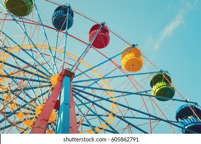 Retro colorful ferris wheel of the amusement park in the blue sky background.