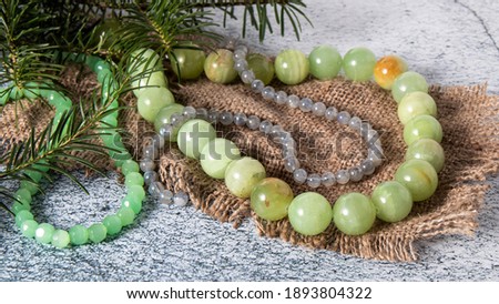 Retro composition of green-yellow  necklace made of natural onyx, agate  (layered chalcedony),  labrador beads and  jade beads on an old linen cloth with fir branches. Onyx stone is energetic amulet. 
