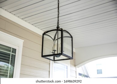 Retro Contemporary Black Metal Iron Hanging Outdoor Light Lamp Lantern With An Old Fashioned Light Bulb Inside Hung On A Front Or Back Porch