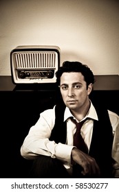 Retro - Dressed Up Man Sitting In Front Of Old Radio Looking At Camera