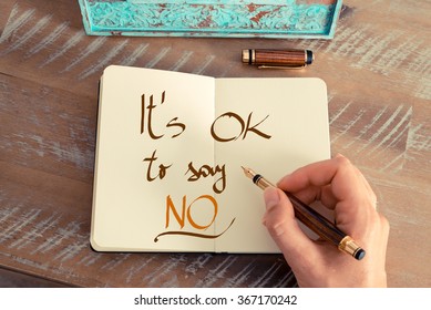 Retro effect and toned image of a woman hand writing a note with a fountain pen on a notebook. Handwritten text IT'S OK TO SAY NO, business success concept