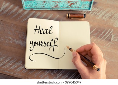 Retro Effect And Toned Image Of A Woman Hand Writing A Note With A Fountain Pen On A Notebook. Handwritten Text Heal Yourself As Success And Evolution Concept Image