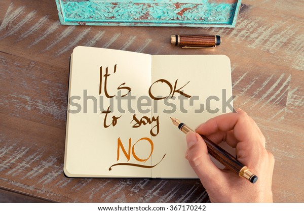 Retro effect and toned image of
a woman hand writing a note with a fountain pen on a notebook.
Handwritten text IT'S OK TO SAY NO, business success
concept