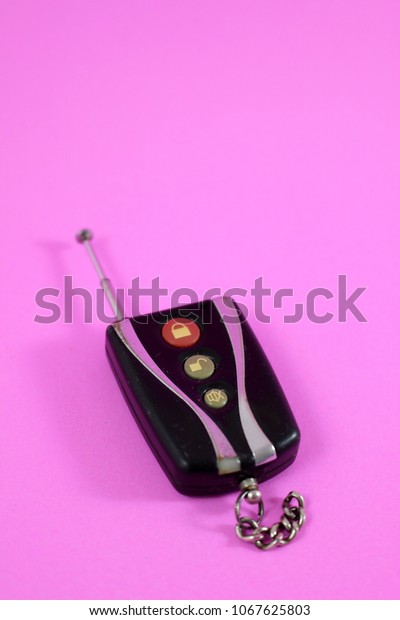 Retro electronic car key with aerial isolated\
on a pink background