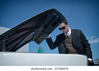 Retro Fifties Mafia Fashion Man Looking In Trunk Of Vintage Car.