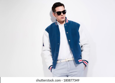 Retro fifties sportive fashion man wearing blue baseball jacket and dark sunglasses. Studio shot against white. - Powered by Shutterstock