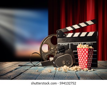 Retro film production accessories placed on wooden planks. Concept of film-making. Red curtain and movie screen on background - Powered by Shutterstock