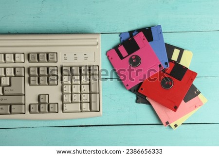 Retro floppy disks and old-fashioned keyboard on pink wooden boards. 80s technology. Top view