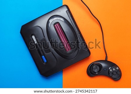 Retro Game Console With Wired Controller On Colorful Blue And Orange Background
