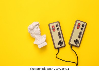Retro gamepads with David bust on yellow background. Gaming. Creative layout. Minimal still life. Flat lay. Top view