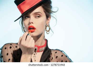 Retro girl paints her lips with lipstick