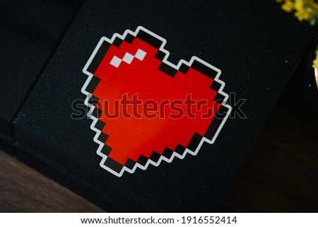 
retro heart-shaped sticker affixed to a black plastic surface