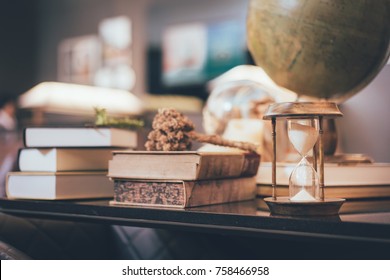 Retro hourglass, blur stack of old books and world desk globe on wooden table, learning and education concepts. - Powered by Shutterstock