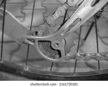 Retro image - Bottom gear of mountain bike derailleur with chain and orange reflector in the background.