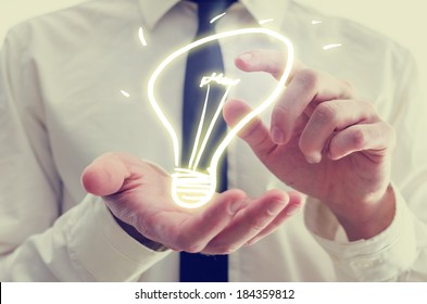 Retro image of businessman holding a creative light bulb icon in his hands conceptual of ideas, inspiration, imagination, and innovation. - Powered by Shutterstock