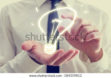 Retro image of businessman holding a creative light bulb icon in his hands conceptual of ideas, inspiration, imagination, and innovation.