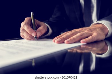 Retro image of lawyer signing important legal document on black desk. Over black background.