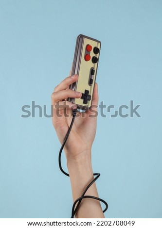 Retro joystick in female hand on a blue background. Retro gaming. Video game