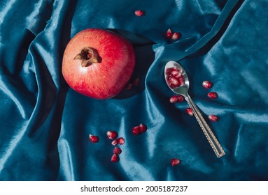 Retro Layout Of Pomegrante And Seeds On The Royal Blue Velvet With Tea Spoon. Minimal Concept Flat Lay.