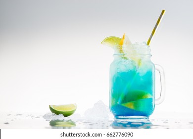 retro mason glass jars of cold blue fresh non-alcoholic cocktail with lime, lemon and yellow drinking straw on light background - Powered by Shutterstock