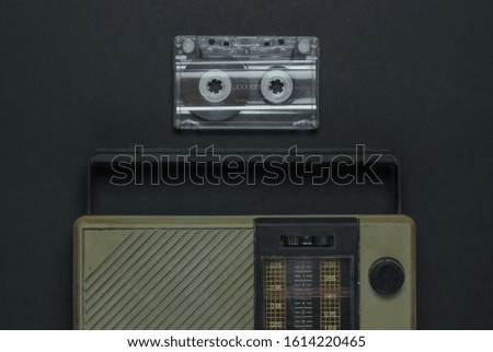 Retro media. Radio receiver, audio cassette on black background. Top view.