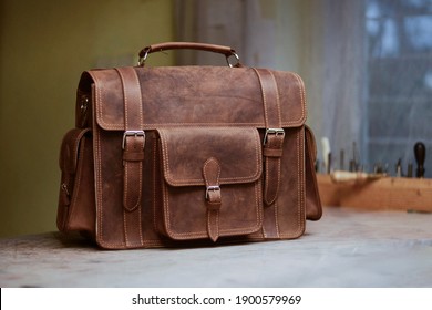 Retro Men's Work Bag Made Of Cowhide. Photo Created In A Bag Workshop. In The Background Are Bag Work Tools. Briefcase Made Of Brown Leather. Satchel To Work. Bag For Men.