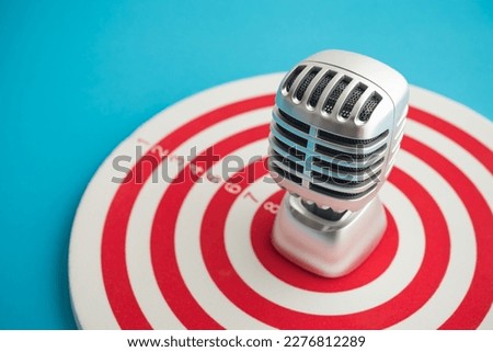 Retro microphone on center of target blue background copy space. Focus on customer feedback, satisfaction, review need for organization improvement and development. Leadership management and strategy.