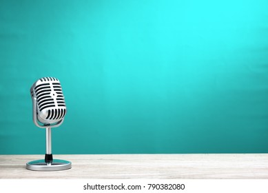 Retro microphone on wooden table with turquoise wall background
