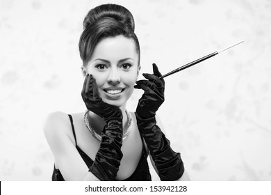 Retro Movie Star Concept. Portrait Of Beautiful Actress In A Great Black Cocktail Dress Smoking A Cigarette With Holder. Perfect Shiny Smile & Skin. Vintage (old Hollywood) Style. Close Up. Copy-space