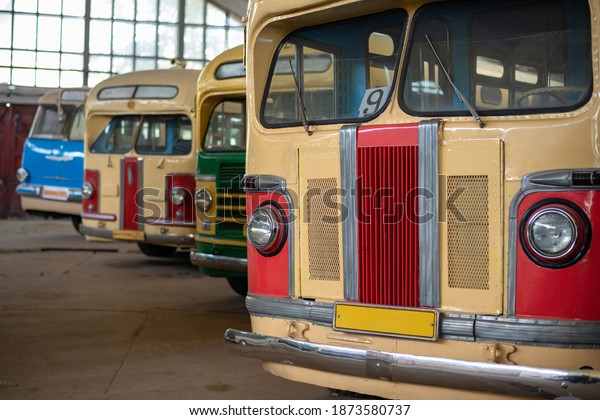 Retro multi-colored buses in a large\
garage with selective focus and bokeh\
background