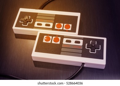 Retro NES console controller with black and red buttons on a metallic table