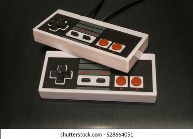 Retro NES console controller with black and red buttons on a metallic table