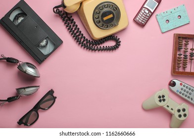 Retro objects on pink background. Rotary telephone, audio cassette, video cassette, gamepad, 3d glasses, tv remote, headphones, push-button phone. Analog media technology of  past. Copy space.