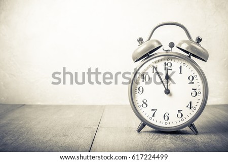 Retro old aged clock on wooden desk. Vintage style sepia photo