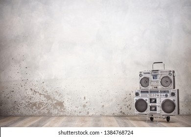 Retro old design ghetto blaster boombox stereo radio cassette tape recorders from circa 1980s on handcart front concrete wall background. Rap and Hip Hop music concept. Vintage style filtered photo