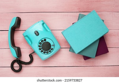 Retro Old Fashioned Blue Rotary Phone And Books On Red Wooden Table. Top View