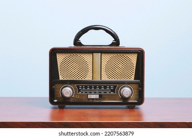 Retro Old Fashioned Radio Receiver On Wooden Table In Front Of The Wall.