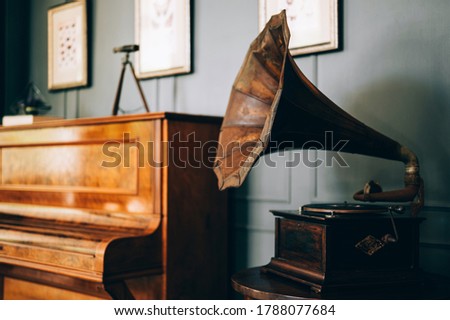 Retro old gramophone radio with horn speaker stands with old piano, Music and nostalgia concept. Vintage style.