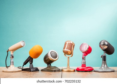 Retro old microphones for press conference or interview on table front gradient aquamarine background. Vintage old style filtered photo