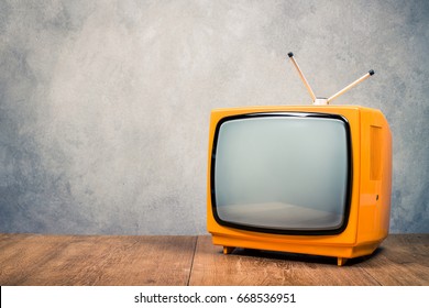 Retro old orange TV receiver on table front textured concrete wall background. Vintage style filtered photo - Shutterstock ID 668536951