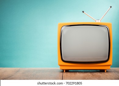 Retro old orange TV receiver on table front gradient aquamarine wall background. Vintage style filtered photo - Shutterstock ID 702291805