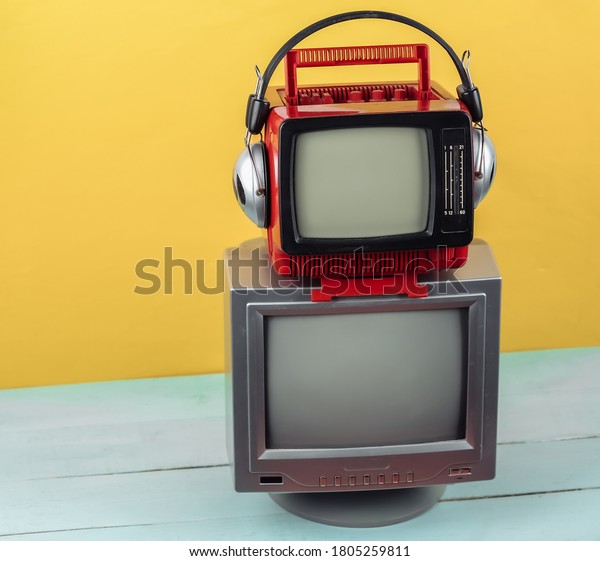 Retro old portable mini tvs with headphones\
on yellow blue\
background.