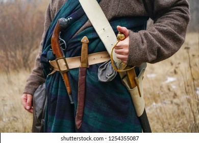 Retro Old Saber, Knife  And Aged Gun Hang On The Belt Of The Scottish Cape