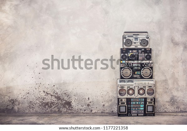 Retro old school\
design ghetto blaster boombox  stereo radio cassette tape recorders\
tower from circa 1980s front concrete wall background. Vintage\
style filtered photo
