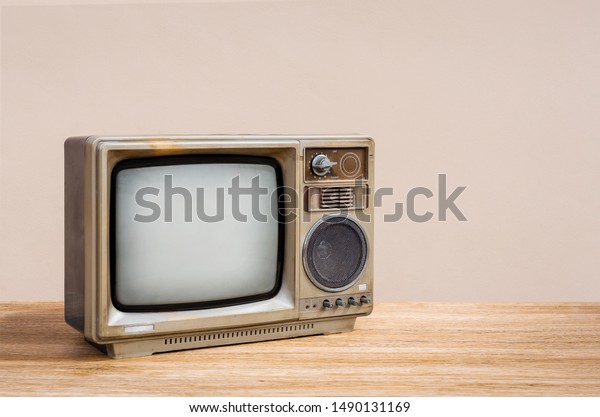 Retro old television receiver on\
wood table with cement wall background. Retro, vintage old\
TV