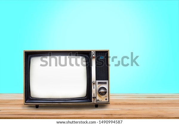 Retro old\
television receiver on wooden table with light blue gradient\
background. Vintage old TV filter\
photo