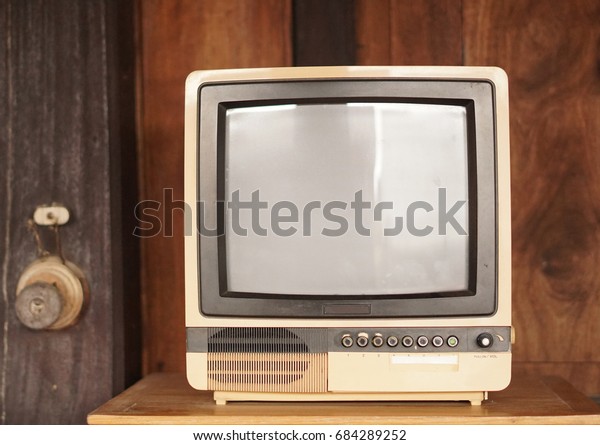 Retro old television in vintage wooden wall\
brown background.